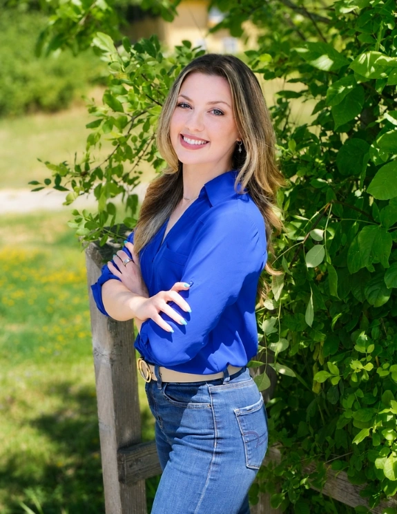 madi-2026 white professional business woman posing outside in bright blue blouse with nature in background